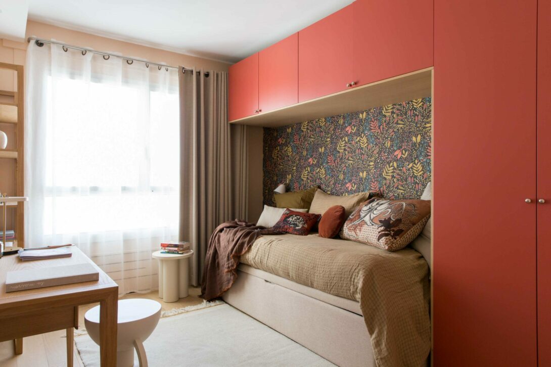 Chambre de jeune fille douillette, dressing avec façades laquées terracotta en alcôve avec lit encastré et papier peint fleuri dans la niche.