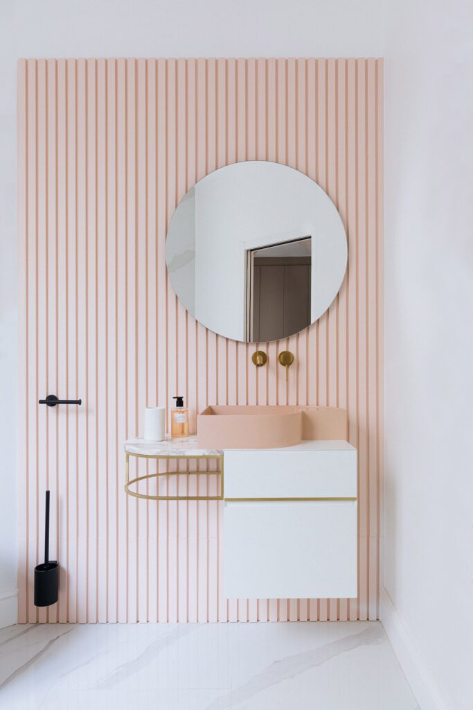 Salle de bain aux tons poudrés, chic et féminine. Meuble vasque avec plateau en marbre et structure en laiton, robinetterie encastrée en laiton brossé.
