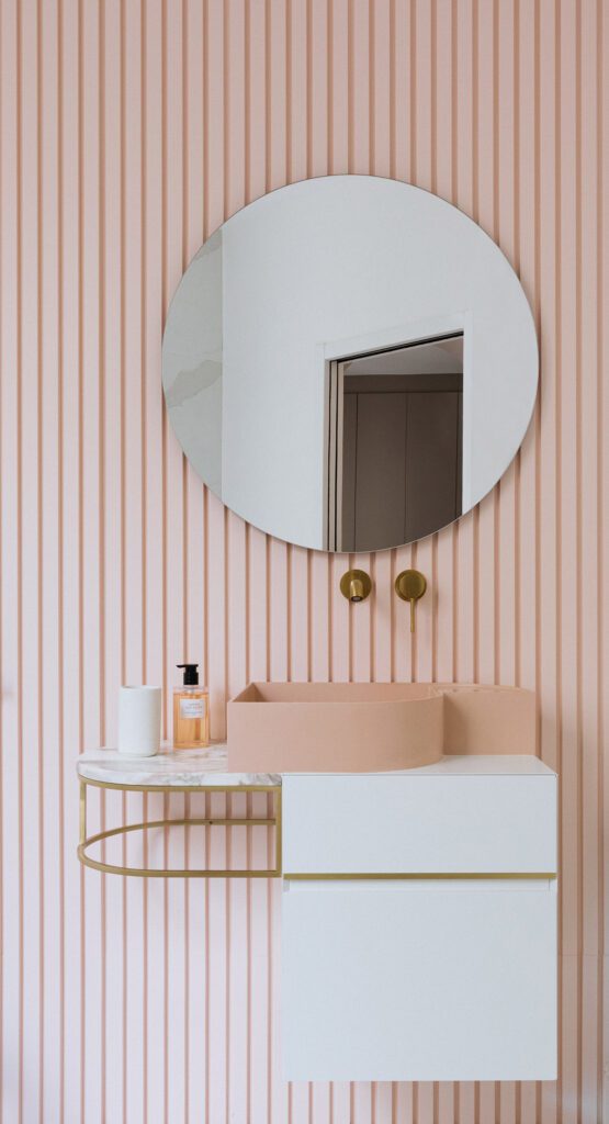 Salle de bain aux tons poudrés, chic et féminine. Meuble vasque avec plateau en marbre et structure en laiton, robinetterie encastrée en laiton brossé.